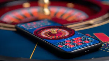 A man celebrating a winning moment on his laptop while gaming symbols float around him, capturing the excitement of PHBINGO games.